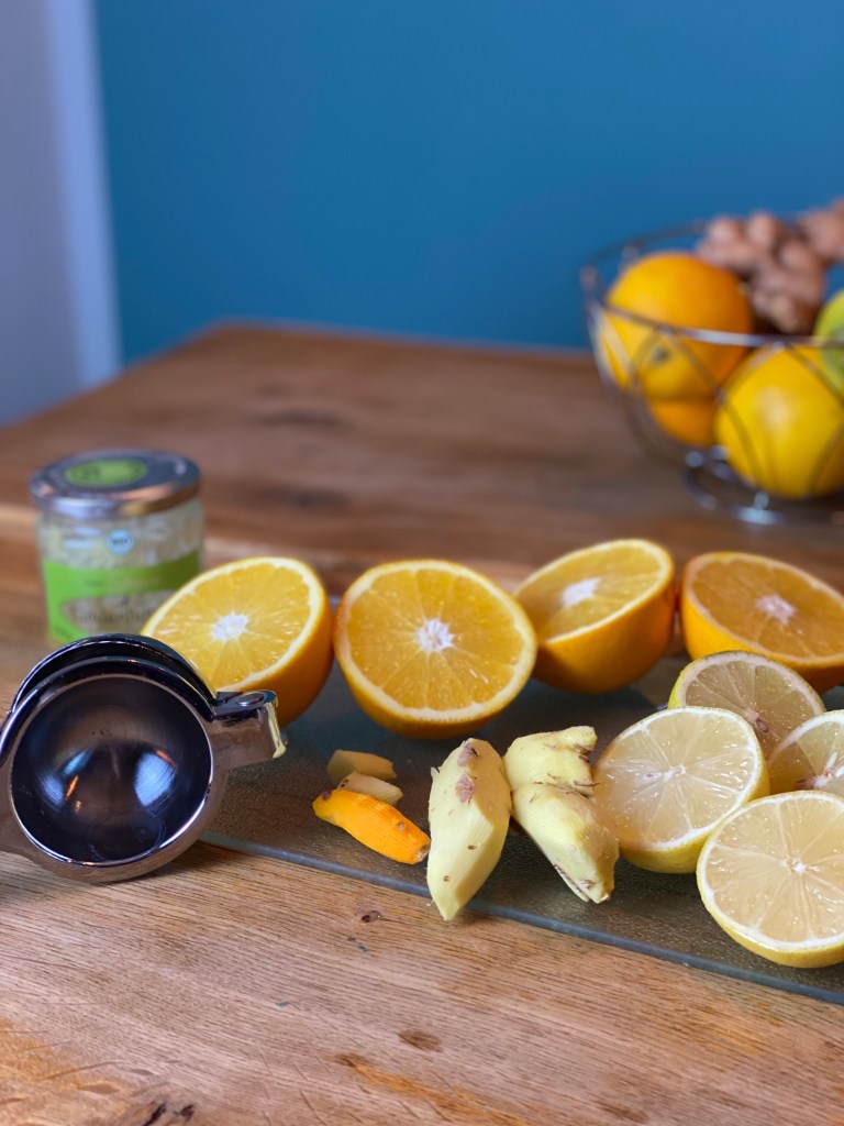 aufgeschnittene Orangen und Zitronen, geschälter Ingwer und Kurkuma für den selfmade Ingwershot auf dem Blog nachhaltigerundgenuss.com